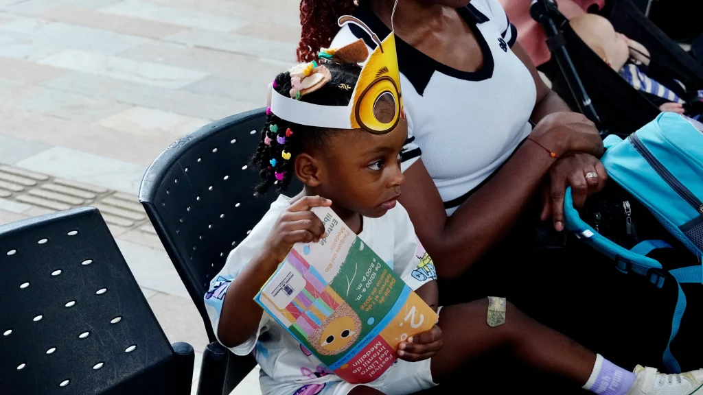 Niña con programación del Festival del Libro Infantil en las manos