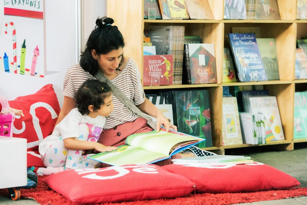 Mujer leyendo un libro con una niña en la Fiesta del libro 2022