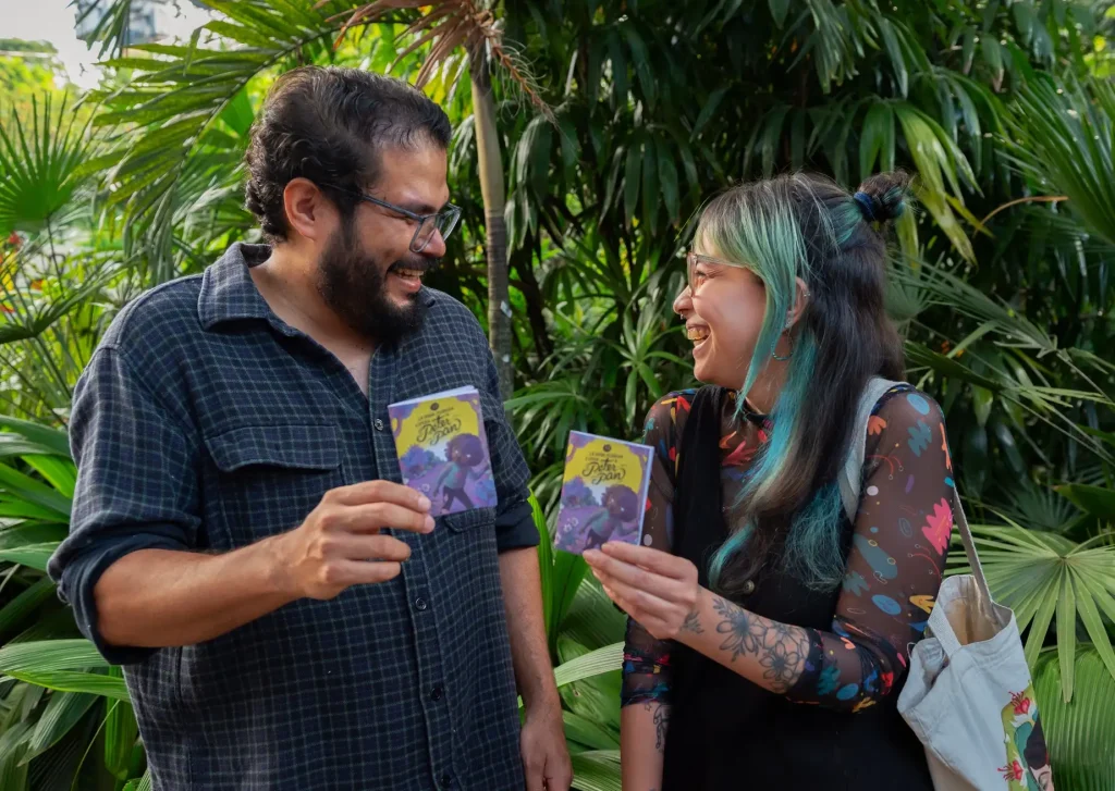 Una mujer y un hombre sonriendo sosteniendo cuenticos amarillos en la Fiesta del Libro 2024